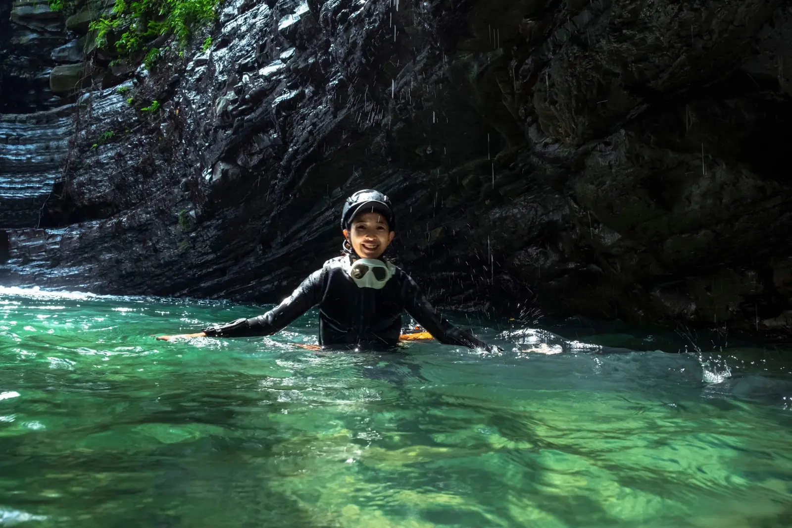 A guest smiling as she wades through a canyon.